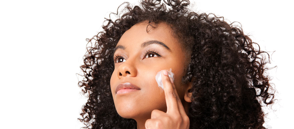 A woman applying lotion to her face